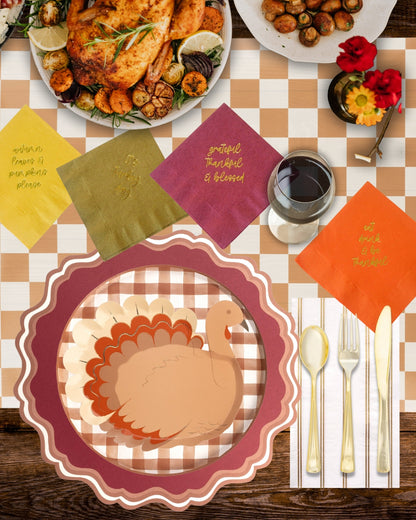 Thanksgiving table setting with turkey-themed plates, checkered tablecloth, and decorative napkins.