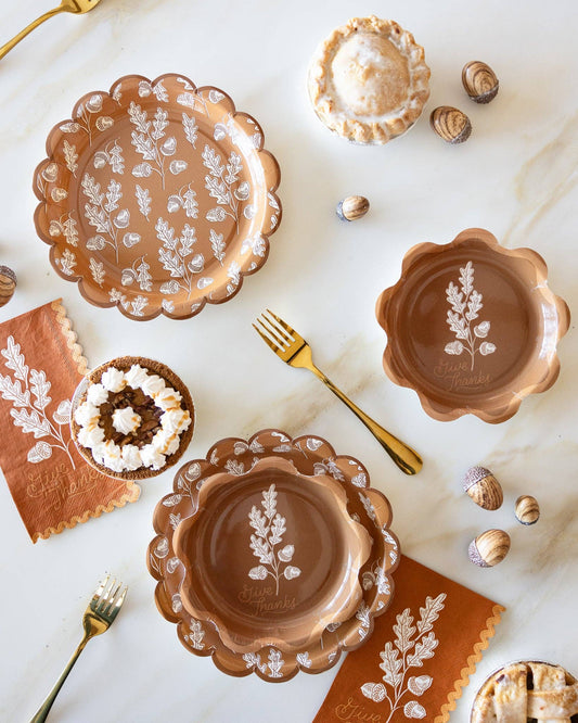 Decorative ceramic plates with floral patterns on a marble surface with gold cutlery and napkins.